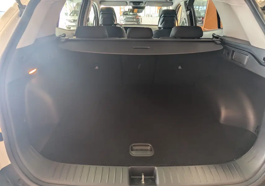 Coffre ouvert vu de l'arrière d'un KIA Sportage blanc 2025, montrant l'espace de chargement et la plage arrière.