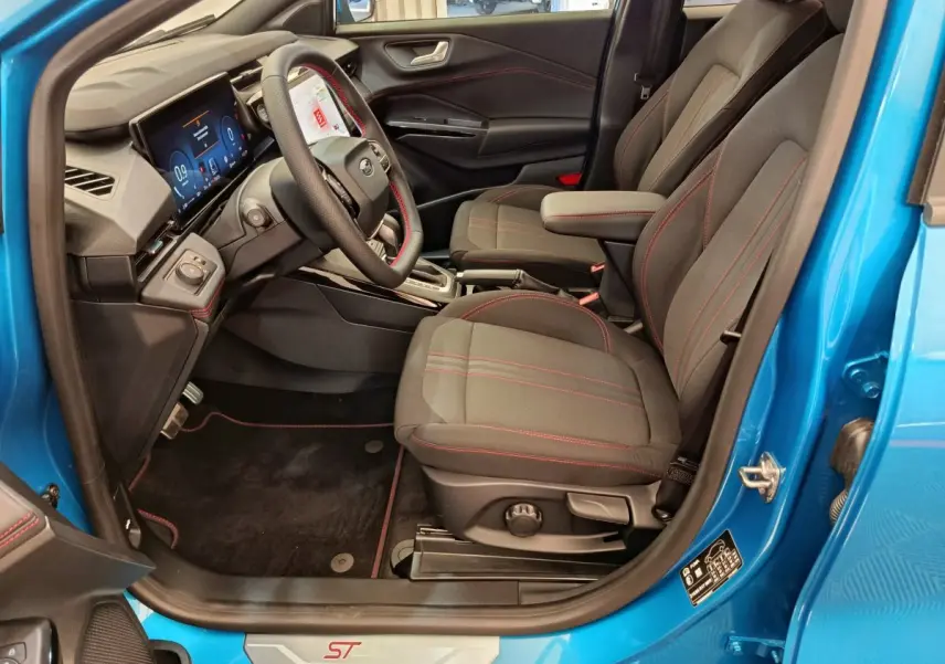Vue intérieure côté conducteur du Ford Puma bleu 2025, sièges noirs avec surpiqûres rouges et tableau de bord numérique.