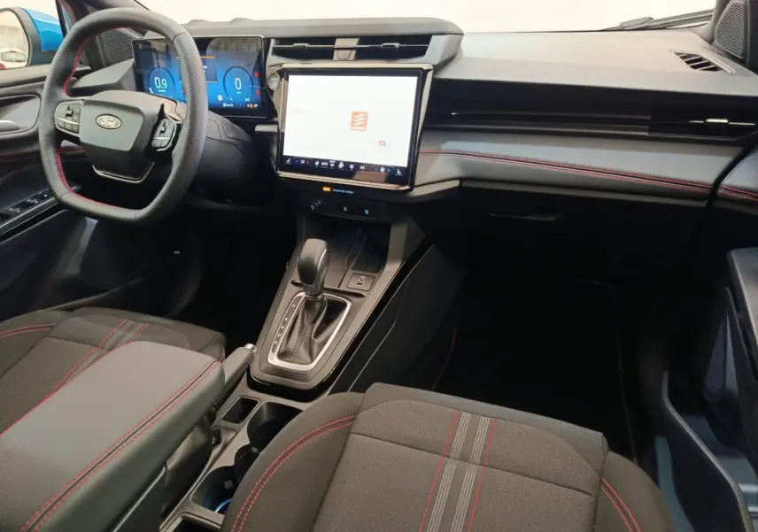 Vue intérieure avant de la Ford Puma 2025, tableau de bord avec écran tactile central et volant multifonctions cuir noir.