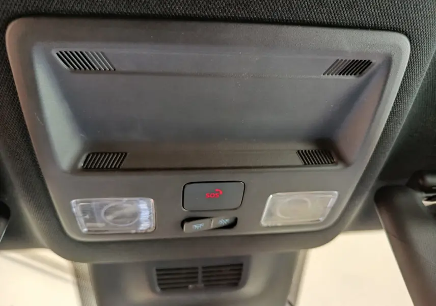 Vue en gros plan du plafonnier intérieur noir avec bouton SOS rouge et éclairages sur Ford Puma bleu 2025.