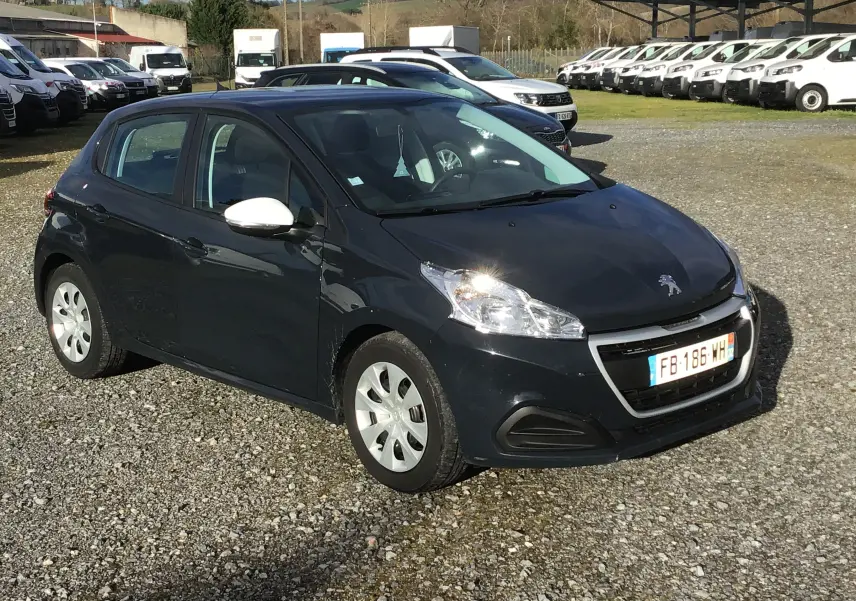 Peugeot 208 bleu foncé vue 3/4 avant droit avec rétroviseurs blancs sur un parking extérieur.