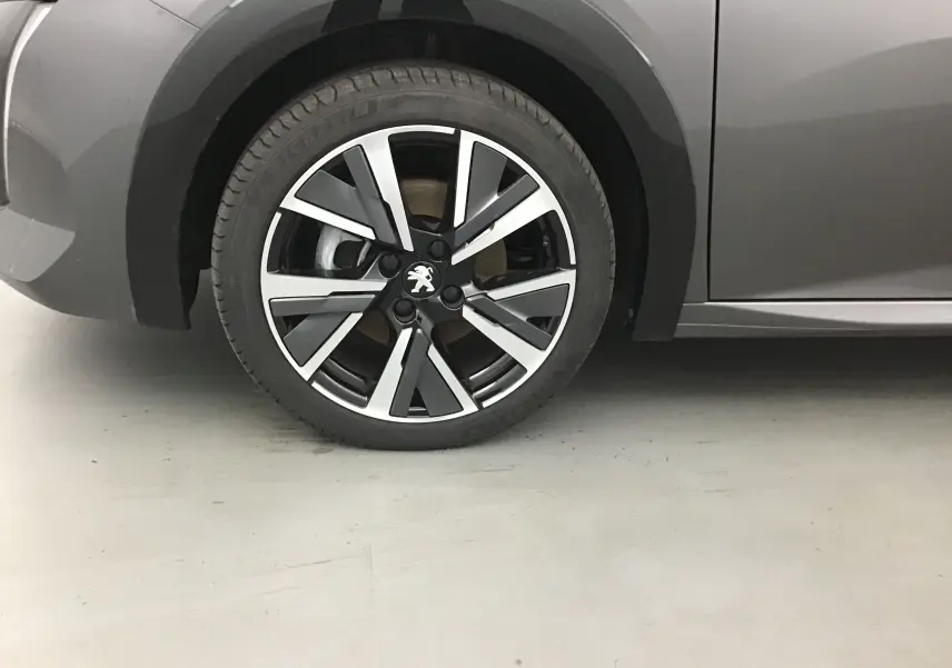 Gros plan sur la roue avant gauche de la Peugeot 208 1.2 PureTech 100 GT S&S gris platinium avec jante alliage noire et argent.