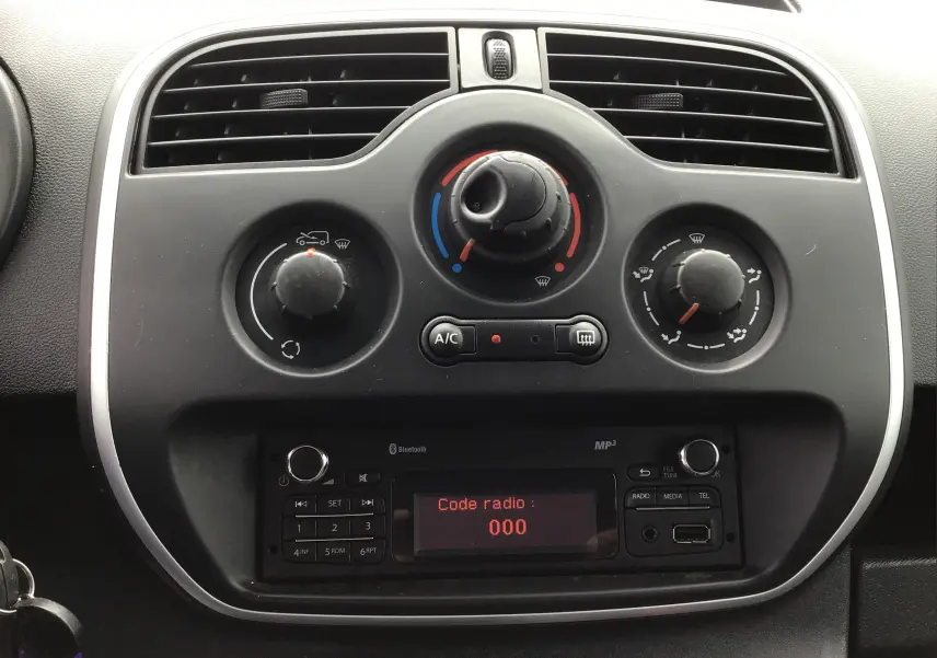 Tableau de bord du Renault Kangoo blanc 2019, vue frontale sur les commandes de climatisation et radio affichant "Code radio : 000".