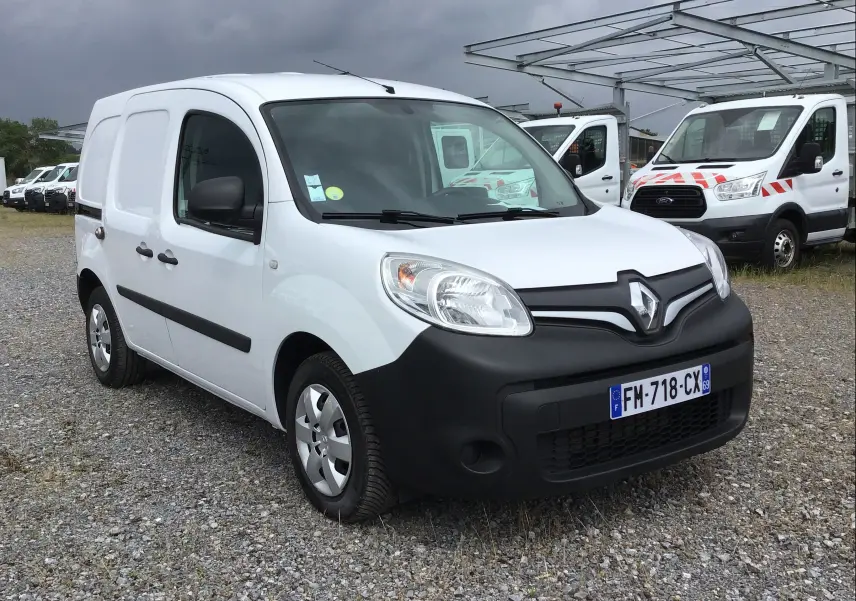 Renault Kangoo blanc vue 3/4 avant droit, fourgonnette utilitaire avec pare-chocs noirs et plaques françaises.