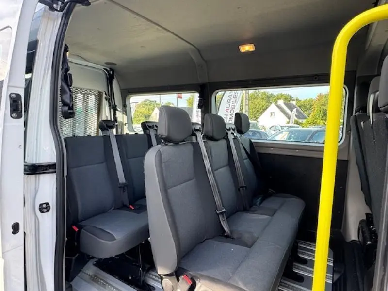 Intérieur du Renault Master Combi blanc, vue côté droit sur les sièges tissu gris et la barre de maintien jaune.