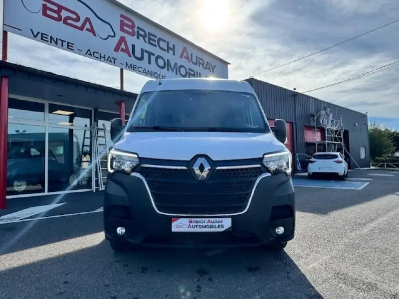 Vue de face d'un Renault Master Combi blanc minéral stationné devant un garage Brech Auray Automobiles.