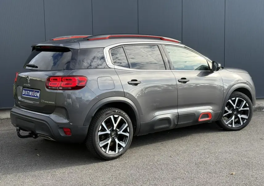 Vue 3/4 arrière droit d'un Citroën C5 Aircross gris Platinium avec jantes alliage 19" et inserts rouges distinctifs.