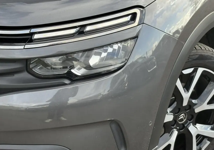 Gros plan sur le phare avant gauche et la jante alliage 19 pouces du Citroën C5 Aircross Gris Platinium.