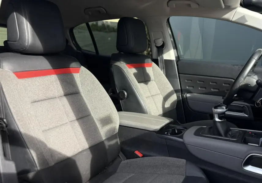 Vue intérieure avant du Citroën C5 Aircross 2020 avec sièges gris clair et inserts rouges sur appuie-têtes et dossier.