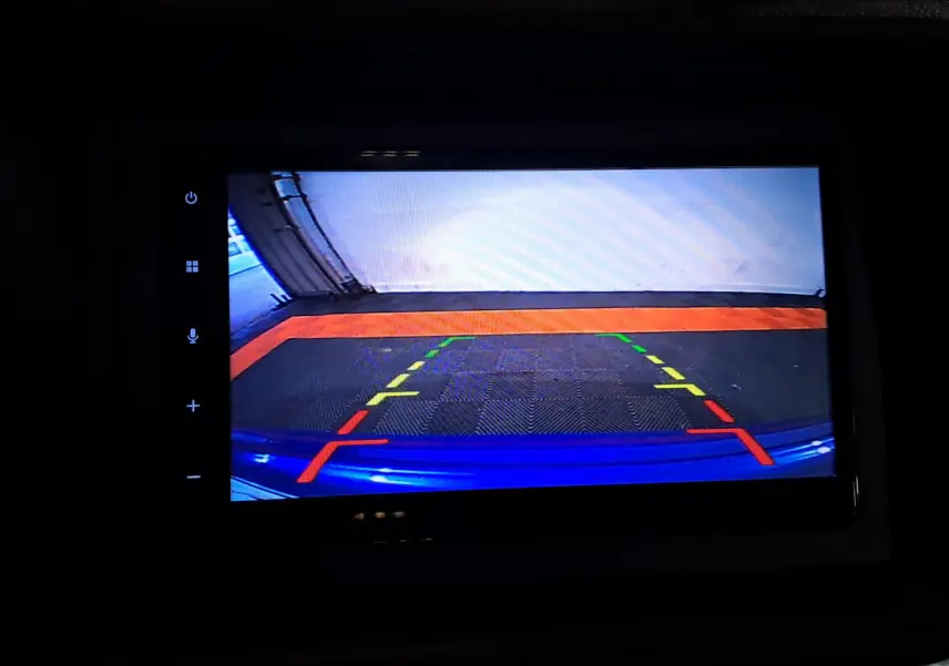 Vue caméra de recul montrant l’arrière bleu de l’AIXAM AMBITION 0.5 CITY GTO avec repères de stationnement colorés.