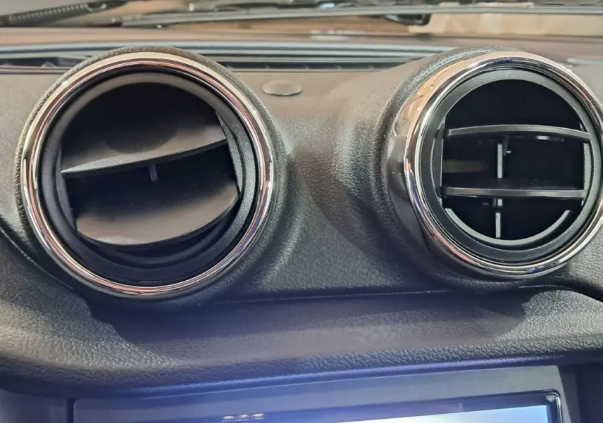 Gros plan sur les deux aérateurs ronds chromés du tableau de bord d’une Aixam Ambition bleu 2026.