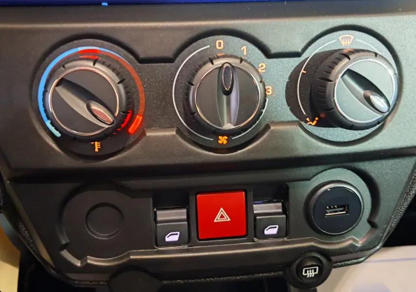 Tableau de bord en gros plan de l'AIXAM AMBITION bleu, montrant les commandes de climatisation et les boutons centraux.