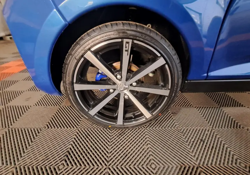 Gros plan sur la roue avant gauche bleu métallisé d'une Aixam Ambition 2026 avec jante noire et détails gris.