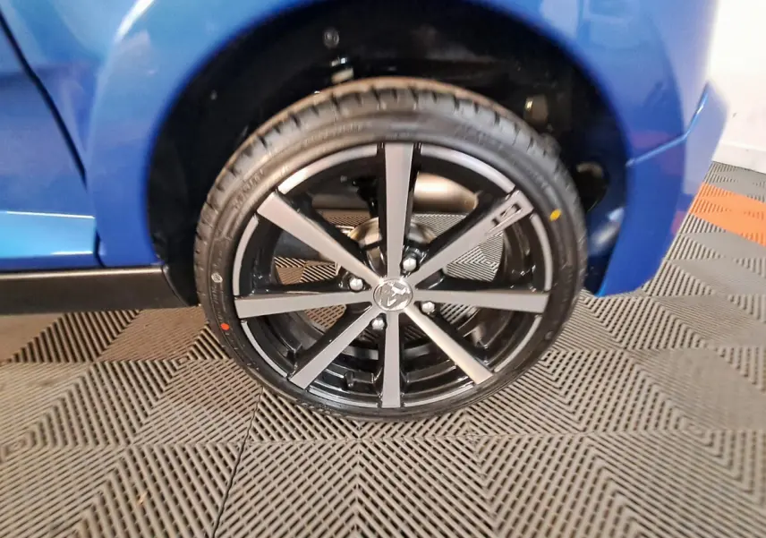 Gros plan sur la roue avant droite de l'AIXAM AMBITION bleue, mettant en valeur la jante noire à branches fines.