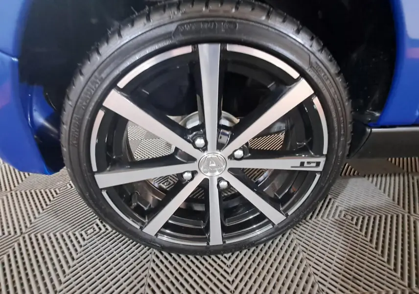 Gros plan sur la jante noire et argentée avec logo AIXAM d'une Aixam Ambition bleu, côté roue avant.