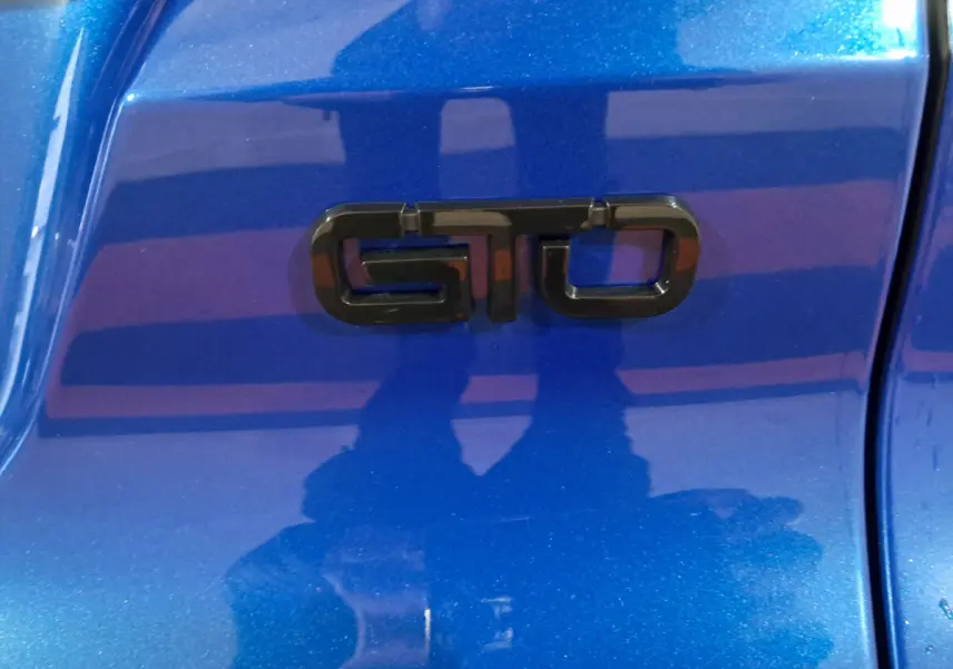 Gros plan sur l’inscription noire GTO sur la carrosserie bleue métallisée d’une Aixam Ambition 2026.