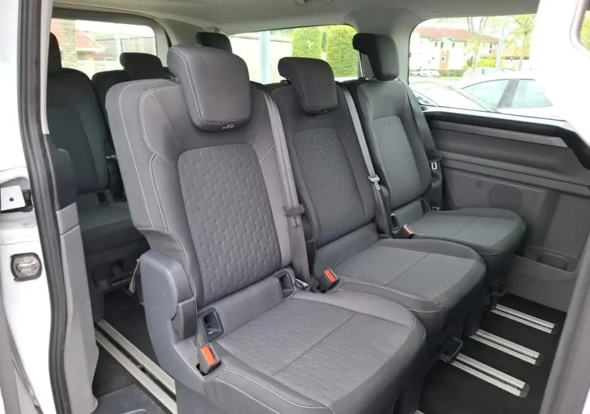 Vue intérieure côté droit des sièges individuels noirs de la 3ème rangée du Ford Tourneo Custom blanc 2024.