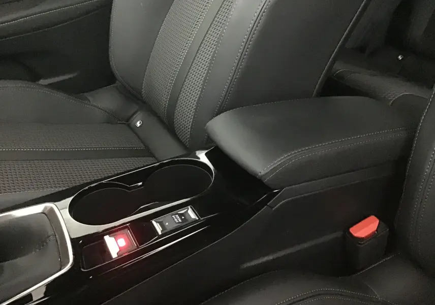 Gros plan sur la console centrale noire et les sièges en cuir noir de la Peugeot 208 1.2 PureTech 100 GT S&S 2023.
