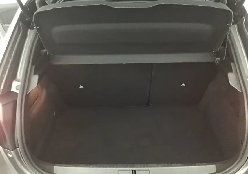 Coffre ouvert vu de dessus du Peugeot 208 gris platinium/noir, montrant un espace de chargement vide et propre.