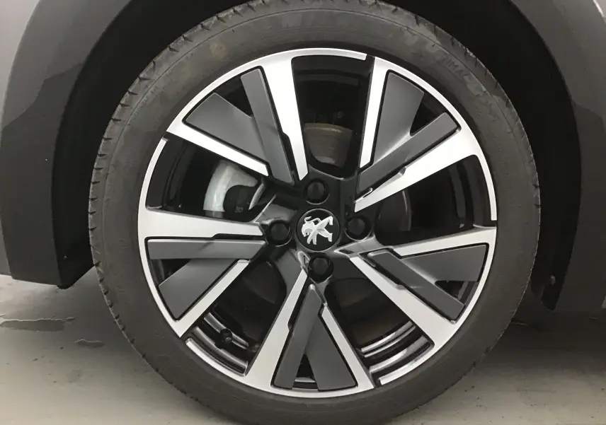 Gros plan sur la roue avant gauche de la Peugeot 208 1.2 PureTech 100 GT S&S gris platinium avec jante alliage noire et argent.