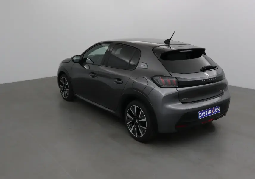 Peugeot 208 gris platinium vue 3/4 arrière côté gauche, avec jantes alliage et logo GT visible.