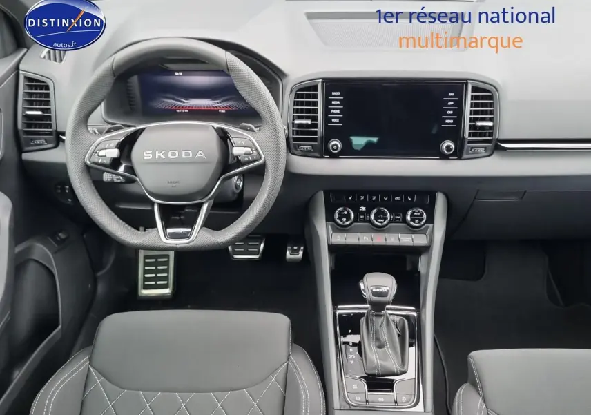 Intérieur du Skoda Karoq 2025 noir, vue frontale du poste de conduite avec volant sport et écran tactile central.