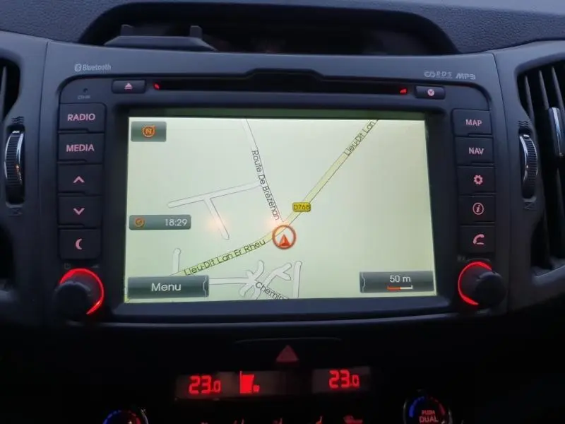 Écran de navigation central du tableau de bord du Kia Sportage blanc 2013, avec commandes autour et affichage GPS.
