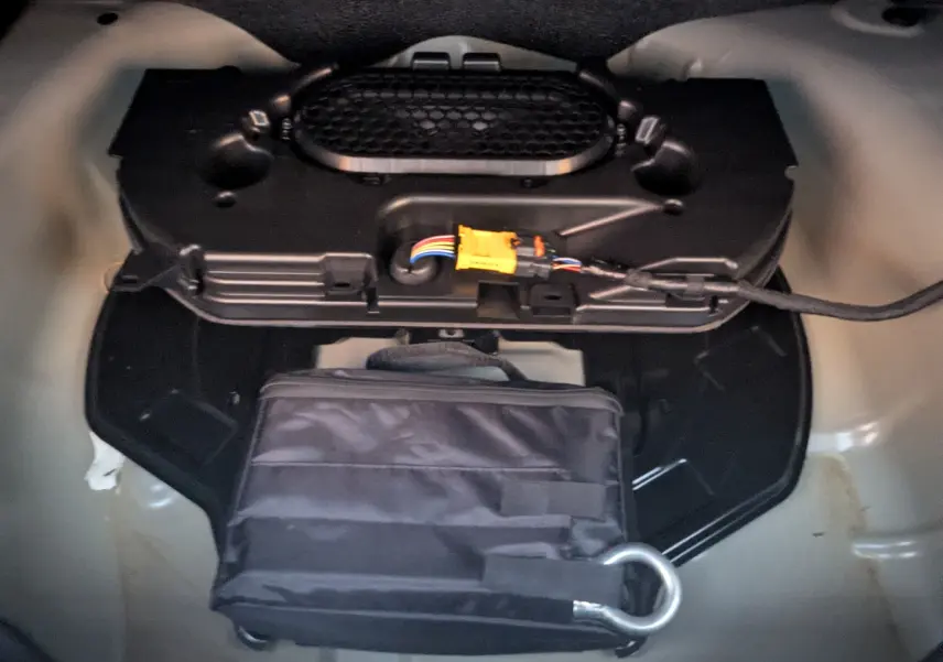 Gros plan sur le coffre de la Citroën C4 2024, montrant un rangement avec sac noir et câblage visible.