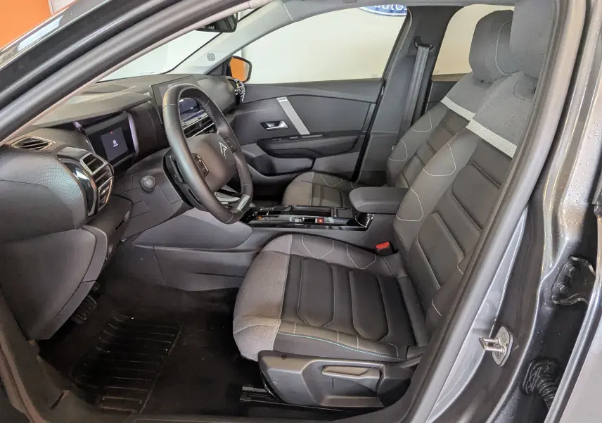 Vue intérieure côté conducteur de la Citroën C4 gris platinium 2024, sièges TEP/tissu gris noir et tableau de bord moderne.