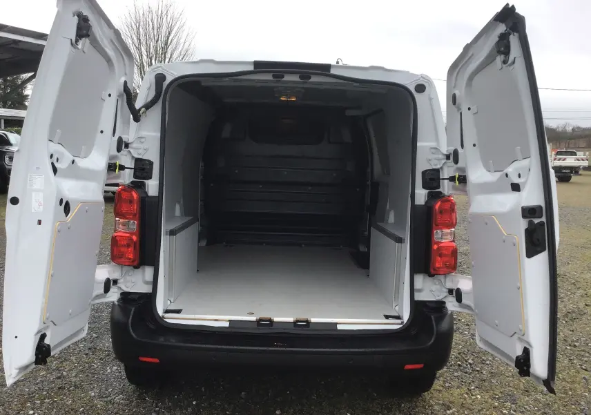 Vue arrière du fourgon FIAT Scudo blanc 2024 avec portes ouvertes et espace de chargement vide aménagé.