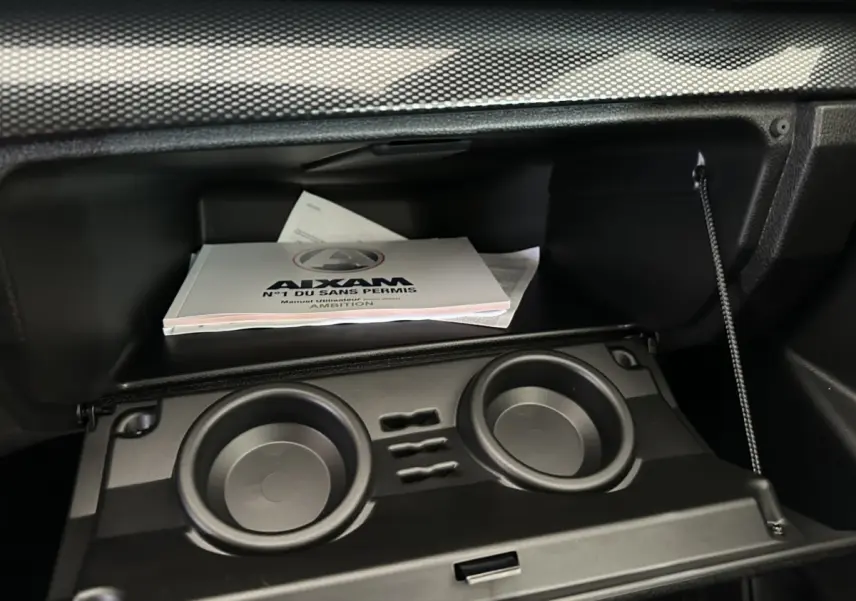 Intérieur de la boîte à gants de l'AIXAM AMBITION 0.5 City Coupe GTI avec manuel utilisateur visible.
