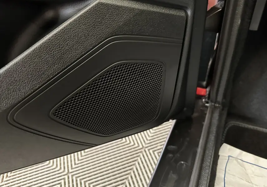 Gros plan sur la porte intérieure noire côté conducteur de l'AIXAM Ambition rouge, avec haut-parleur intégré visible.