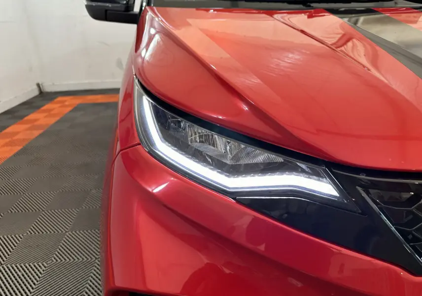 Gros plan sur l'avant gauche rouge de l'AIXAM AMBITION 0.5 CITY COUPE GTI avec phares LED allumés.