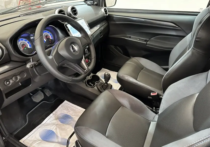 Vue intérieure côté conducteur de l'AIXAM Ambition 2026, montrant le volant, tableau de bord et sièges noirs et gris.