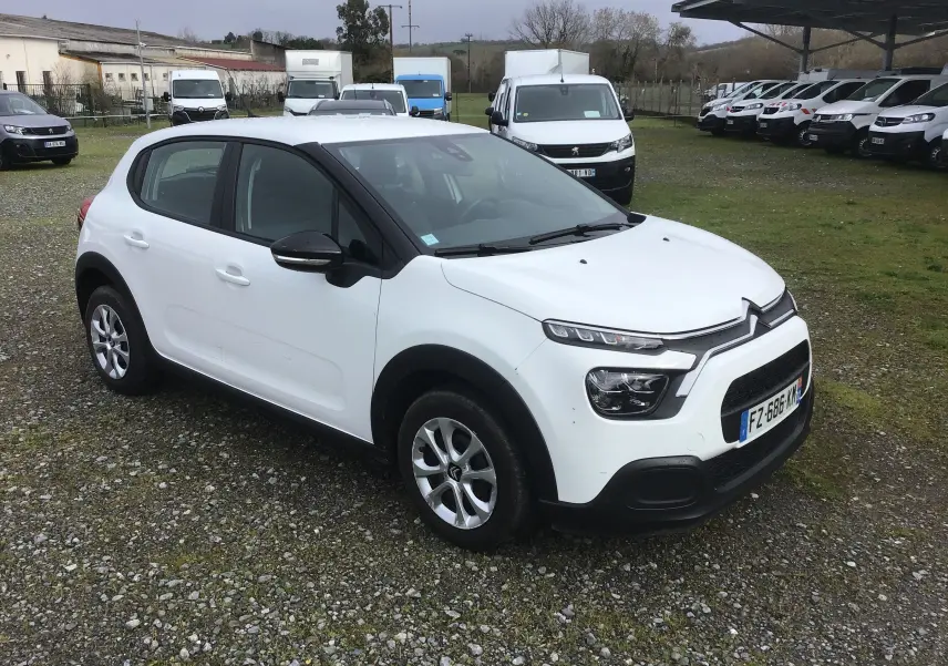 Citroën C3 blanche vue 3/4 avant droit, avec protections noires sur les bas de caisse et calandre distinctive.