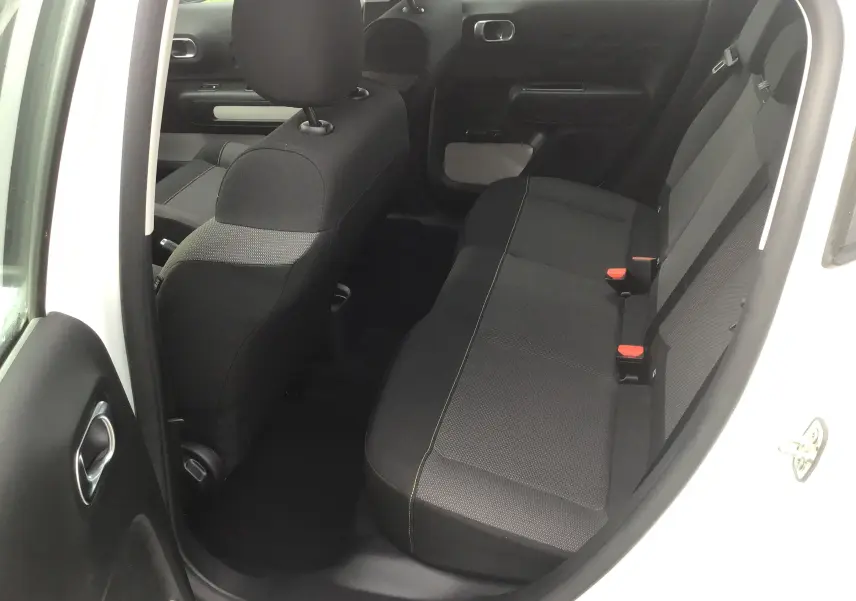 Vue intérieure arrière côté gauche d'une Citroën C3 blanche 2021, montrant les sièges arrière en tissu noir avec surpiqûres contrastantes.