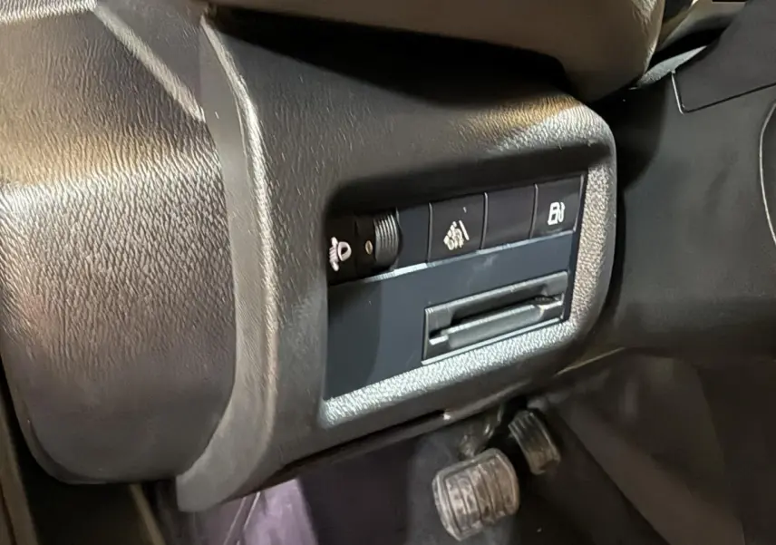 Gros plan sur les commandes noires sous le tableau de bord côté conducteur du Citroën C5 Aircross Hybrid bleu.