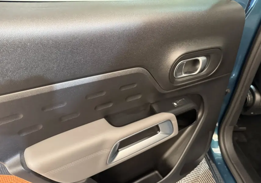 Gros plan sur la porte avant gauche bleu du Citroën C5 Aircross Hybrid avec accoudoir beige et poignée argentée.