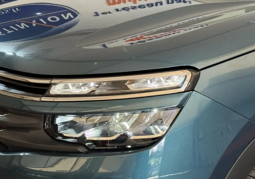 Gros plan sur le phare avant droit du Citroën C5 Aircross Hybrid bleu, mettant en valeur ses feux LED et la calandre chromée.