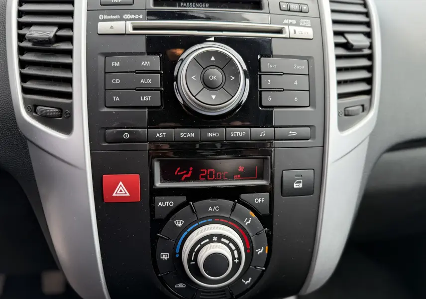 Vue rapprochée du tableau de bord central de la Kia Venga gris 2013, mettant en valeur la console audio et la climatisation digitale.
