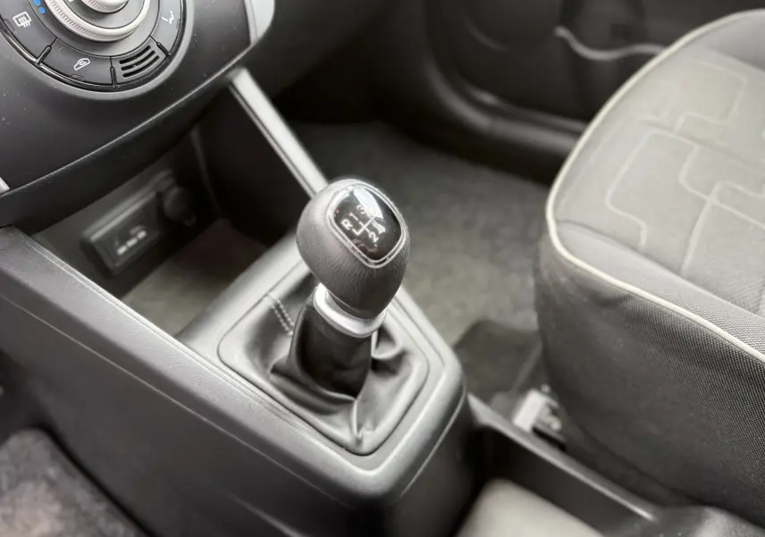 Gros plan sur le levier de vitesses manuel noir et la console centrale d'une Kia Venga 1.4 i 90 Active de 2013.