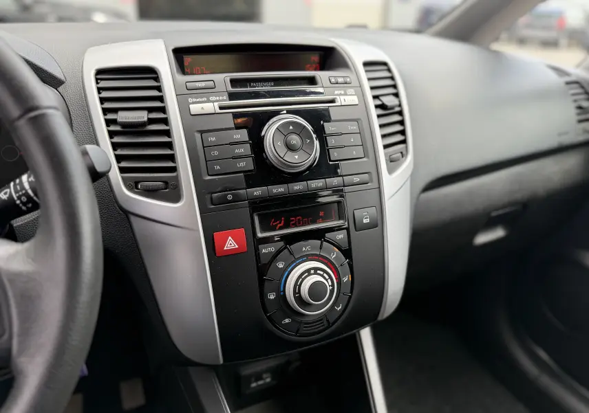 Vue intérieure centrée sur la console centrale noire et grise du Kia Venga 1.4 i 90 ACTIVE avec commandes climatisation et audio.