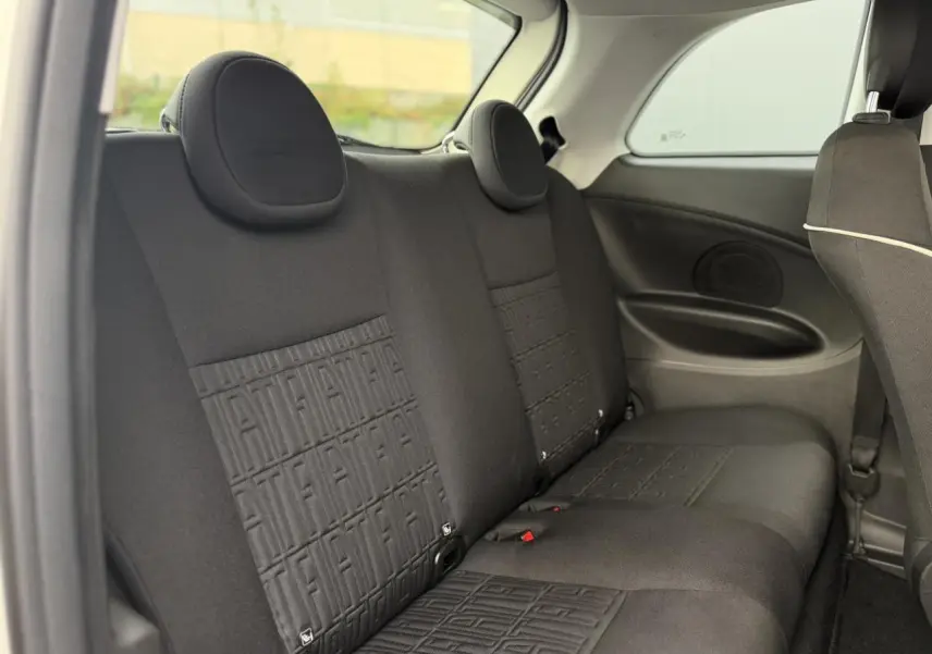 Vue intérieure sur la banquette arrière noire avec motifs Fiat embossés dans une Fiat 500 électrique blanche.