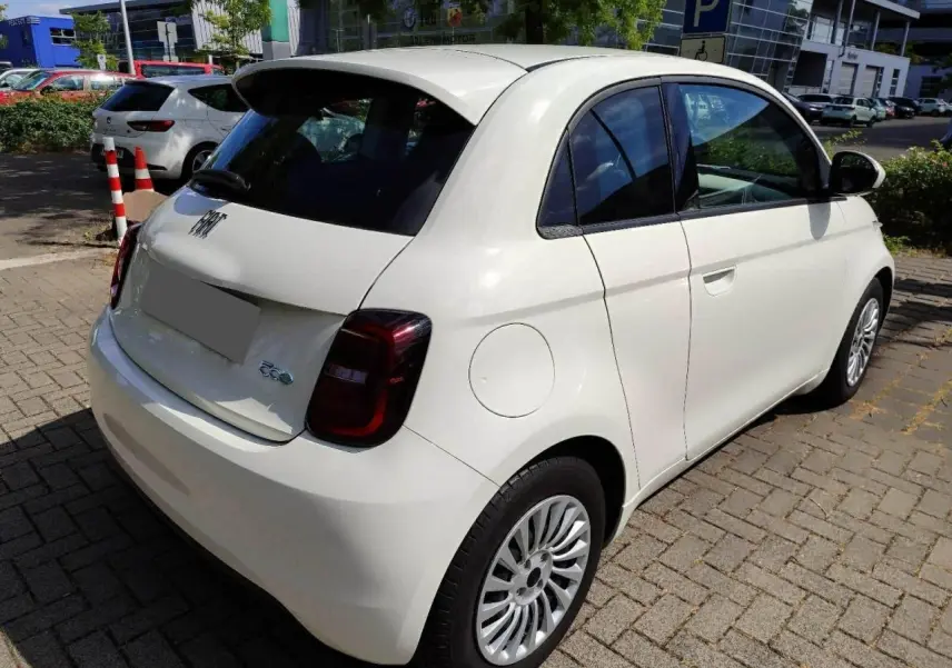 Vue intérieure côté droit de la FIAT 500 électrique 2024, sièges noirs avec surpiqûres blanches et motifs FIAT embossés.
