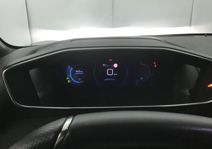 Tableau de bord numérique de la Peugeot 208 1.2 PureTech 100 GT, affichant vitesse et autonomie, vue frontale intérieure.