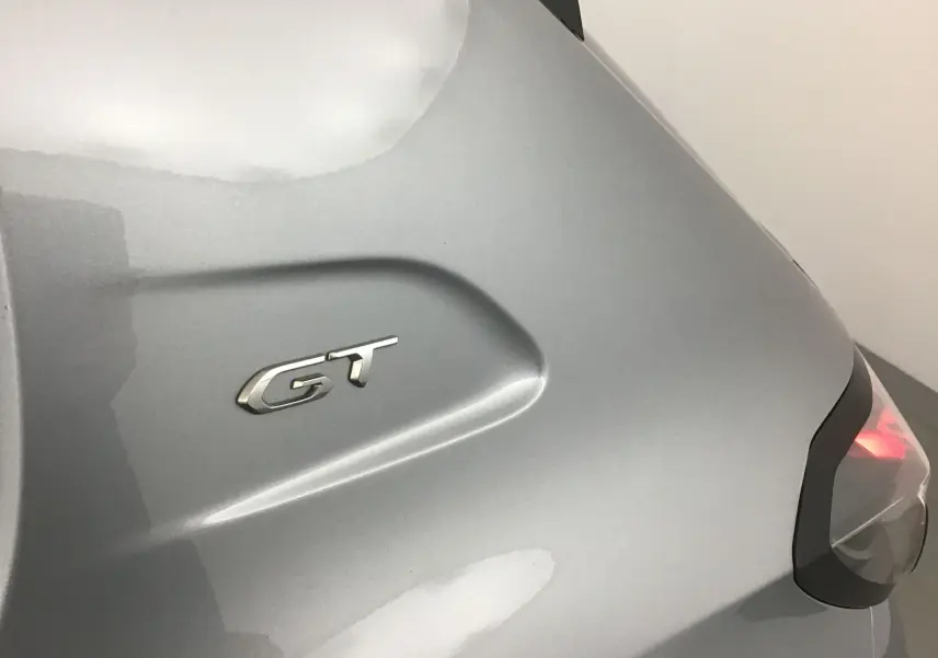 Gros plan sur l'arrière gris Artense d'une Peugeot 208 GT 2023 avec feu arrière allumé et logo GT visible.