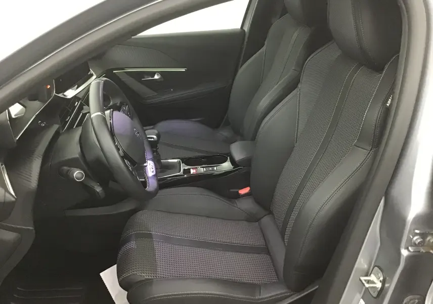 Vue intérieure côté conducteur du Peugeot 208 1.2 PureTech 100 GT S&S 2023 avec sièges en cuir noir et volant sport.