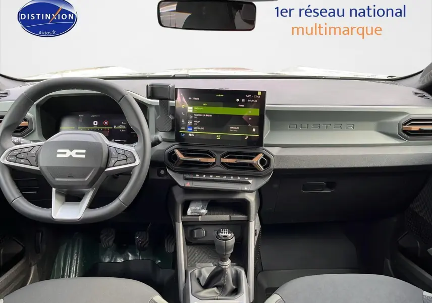 Intérieur du Dacia Duster 2025 avec tableau de bord moderne, écran tactile et volant multifonction noir.