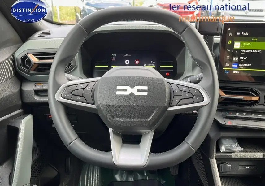 Vue rapprochée du volant multifonction et du tableau de bord numérique du Dacia Duster 2025, intérieur moderne noir et gris.