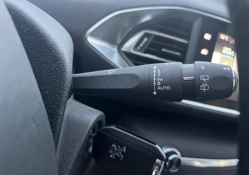 Gros plan sur la commande d'essuie-glace et la clé Peugeot dans l'habitacle de la 308 blanche de 2017.